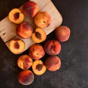 Top-down view of fresh and juicy peaches on a wooden cutting board with dark background.