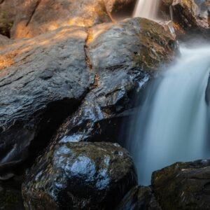 Tranquil waterfall gently flowing over large rocks amidst nature, creating a serene landscape.