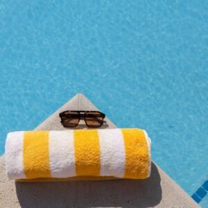 Relax by the pool with striped towel and sunglasses under the summer sun.