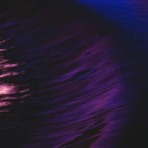 Swirling abstract art with vibrant purple and pink reflections in water, evoking a sense of motion and flow.