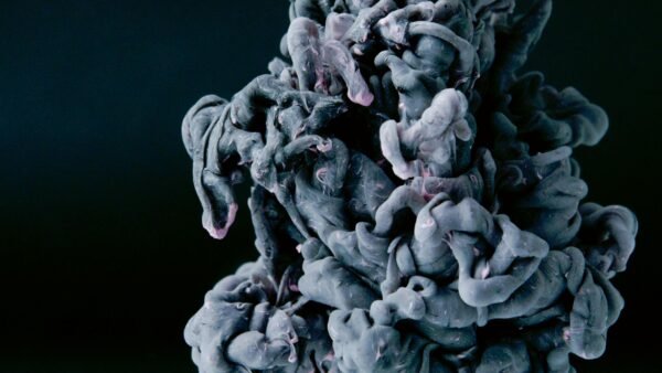 Dynamic abstract photograph of swirling ink and smoke against a black background, evoking fluid motion.