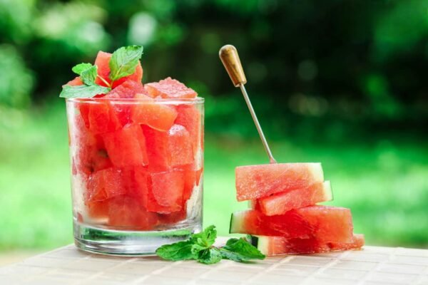 Close-up of fresh watermelon cubes in a glass with mint leaves, perfect for summer refreshment.
