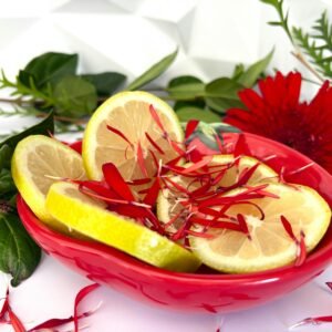 Fresh lemon slices in a red bowl with flowers and greenery.