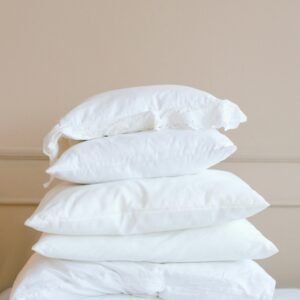 A stack of white pillows on a neutral background, showcasing elegance and simplicity.
